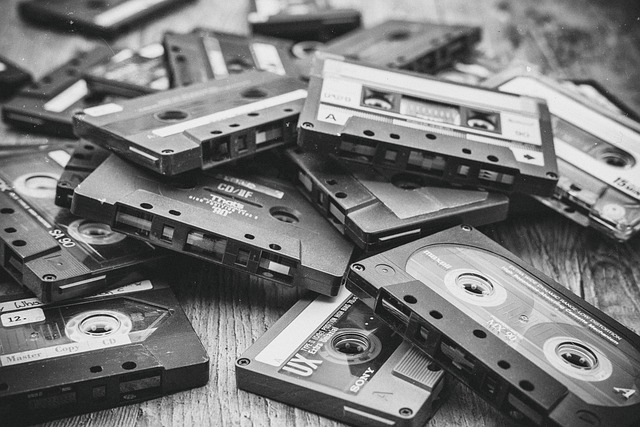 Schwarz-weiß-Fotografie eines Haufens alter Audiokassetten auf einer Holzoberfläche. Retro-Kassetten als Symbol für Jugend-Songs und Erinnerungen.