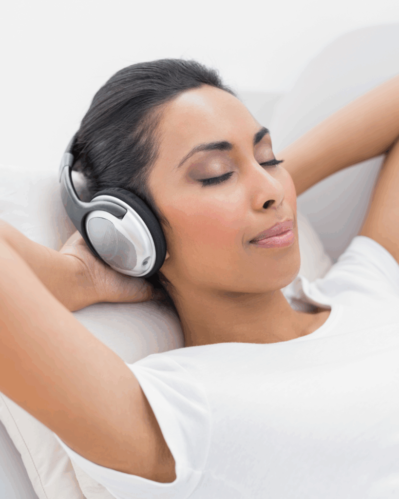 Frau mit Kopfhörern und geschlossenen Augen genießt beruhigende Musik – Musik senkt Cortisol und fördert Entspannung.