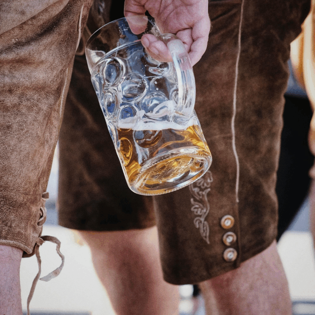 Bild zum Thema Musik beim Vereinsfest: Person in Lederhose hält Maßkrug Bier – typische Stimmung beim Frühschoppen auf einem Vereinsfest.
