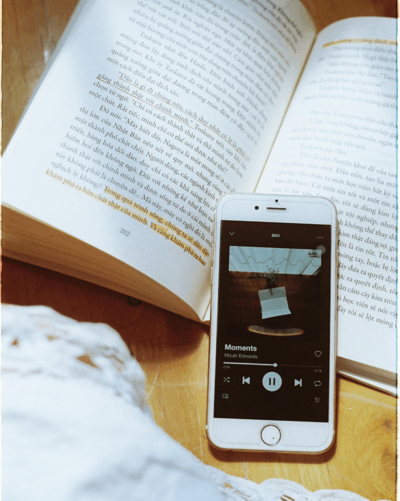 Smartphone mit geöffneter Playlist liegt auf einem Buch – Musik beim Lernen