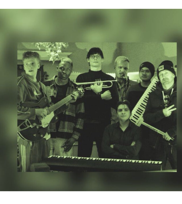 Sieben Männer posieren mit Musikinstrumenten, darunter Gitarre, Trompete, Saxophon, Keytar und Keyboard, vor einem grünen Hintergrund in Innenraum.