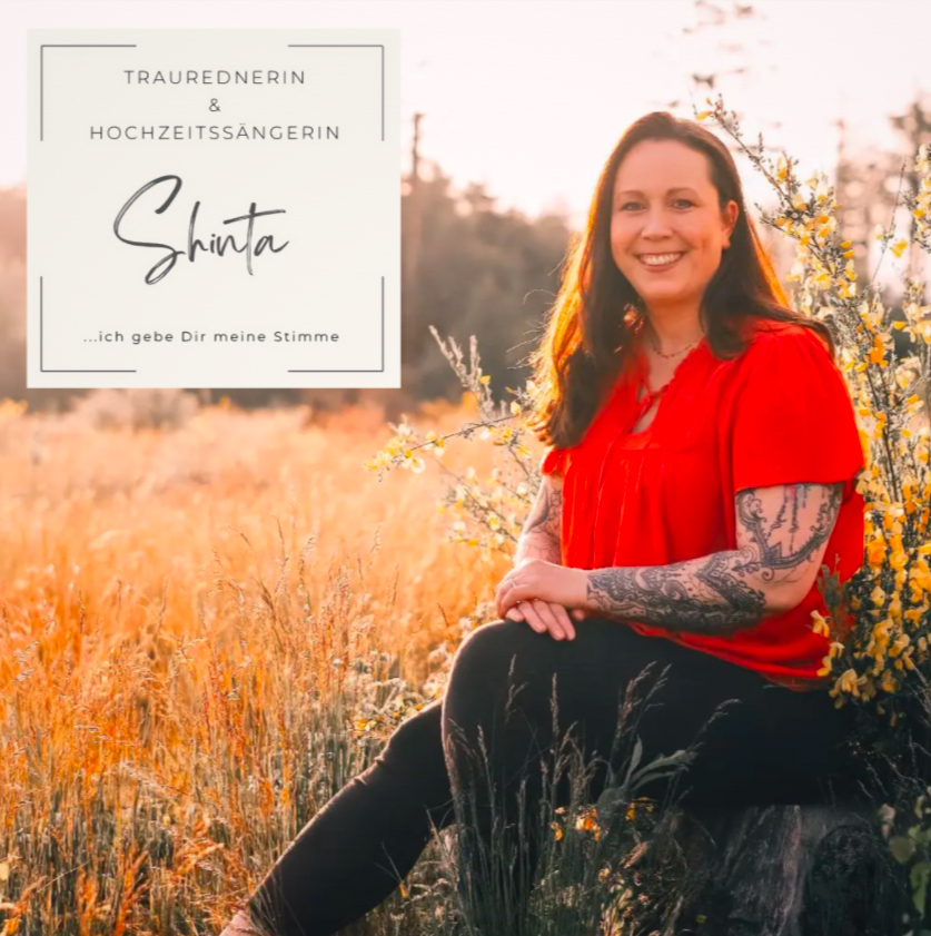 Frau mit langen dunklen Haaren und roten Oberteil sitzt bei Sonnenuntergang auf einem Baumstamm in einem goldenen Feld mit blühenden Zweigen, daneben Textkasten mit der Aufschrift Traurednerin & Hochzeitssängerin Shinta ...ich gebe Dir meine Stimme